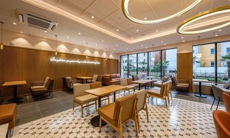 Un café moderno con paneles de madera, asientos cómodos y grandes ventanales que dan al exterior.
