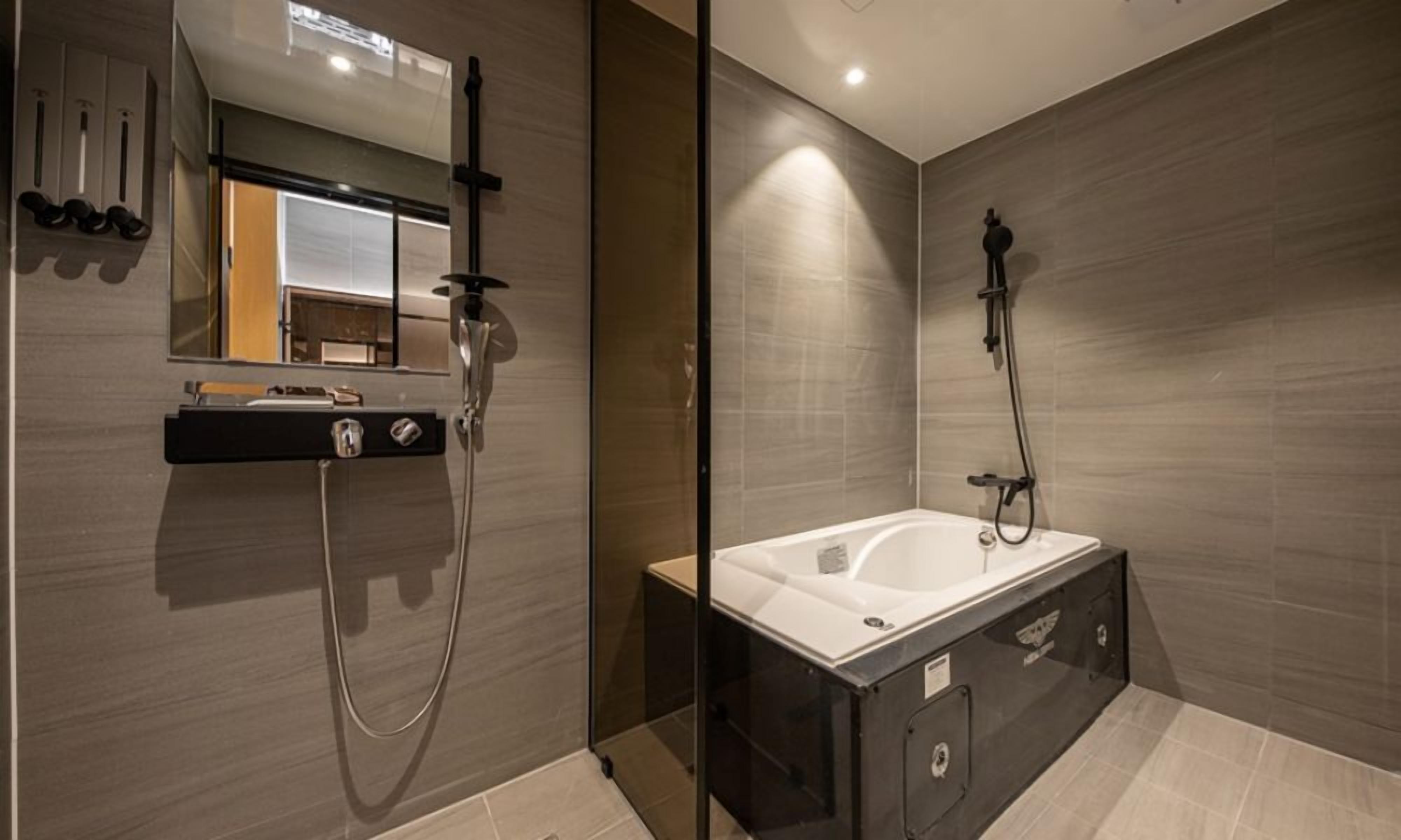 Ein modernes Badezimmer mit einer gläsernen Duschkabine, einer freistehenden Badewanne und einem Waschtisch mit Spiegel und Handtuchhalter.