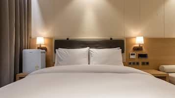Una camera d'albergo con un letto, comodini, una lampada, un termostato e un pannello di controllo a parete.