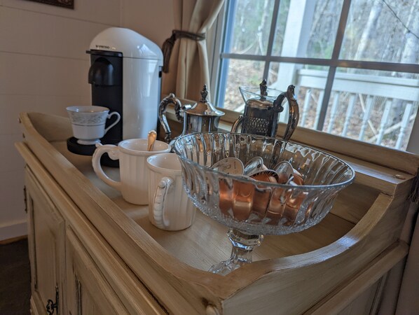 A kitchen counter with a coffee maker, a glass bowl, and two white mugs.