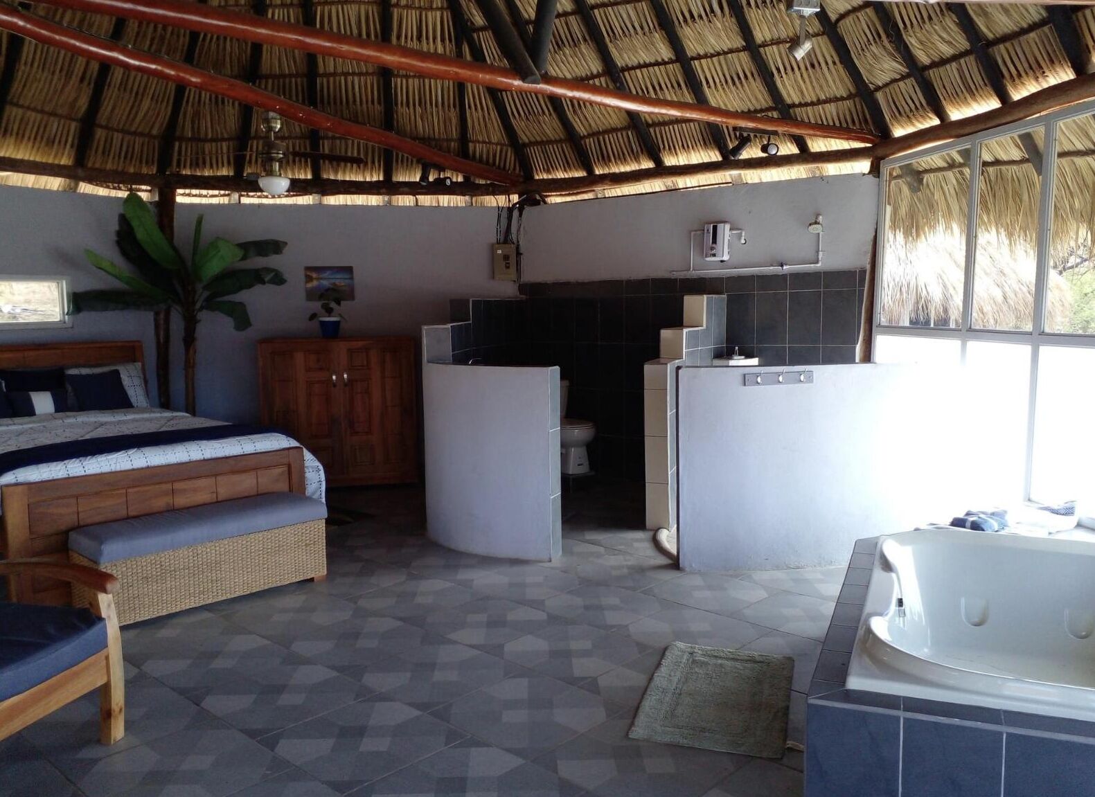 Een kamer met een bed, een klein keukenhoekje, een badkamer en een whirlpool.