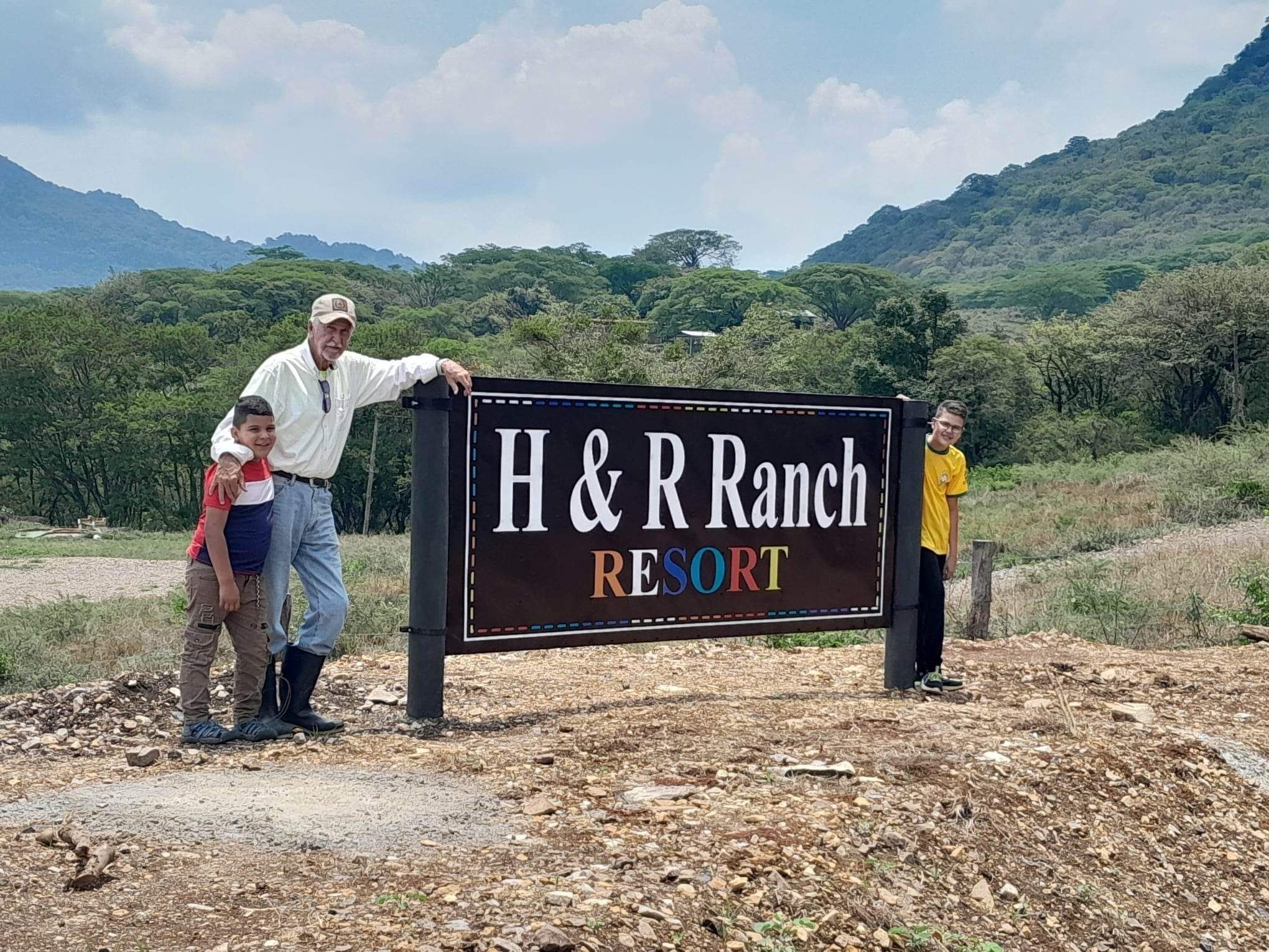 A sign for H&R Ranch Resort with a mountainous backdrop.