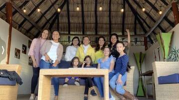Un grupo de personas reunidas bajo un tejado de paja con una mesa en el centro.