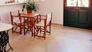 Una habitación con una mesa de comedor, sillas, una lámpara colgante, una planta en maceta y una puerta que ofrece vistas al exterior.