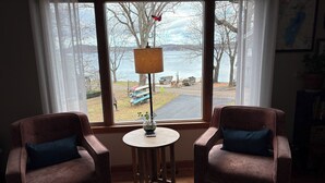Une pièce avec deux fauteuils marron, une petite table avec une lampe et une vue sur un quai et l’eau à l’extérieur.