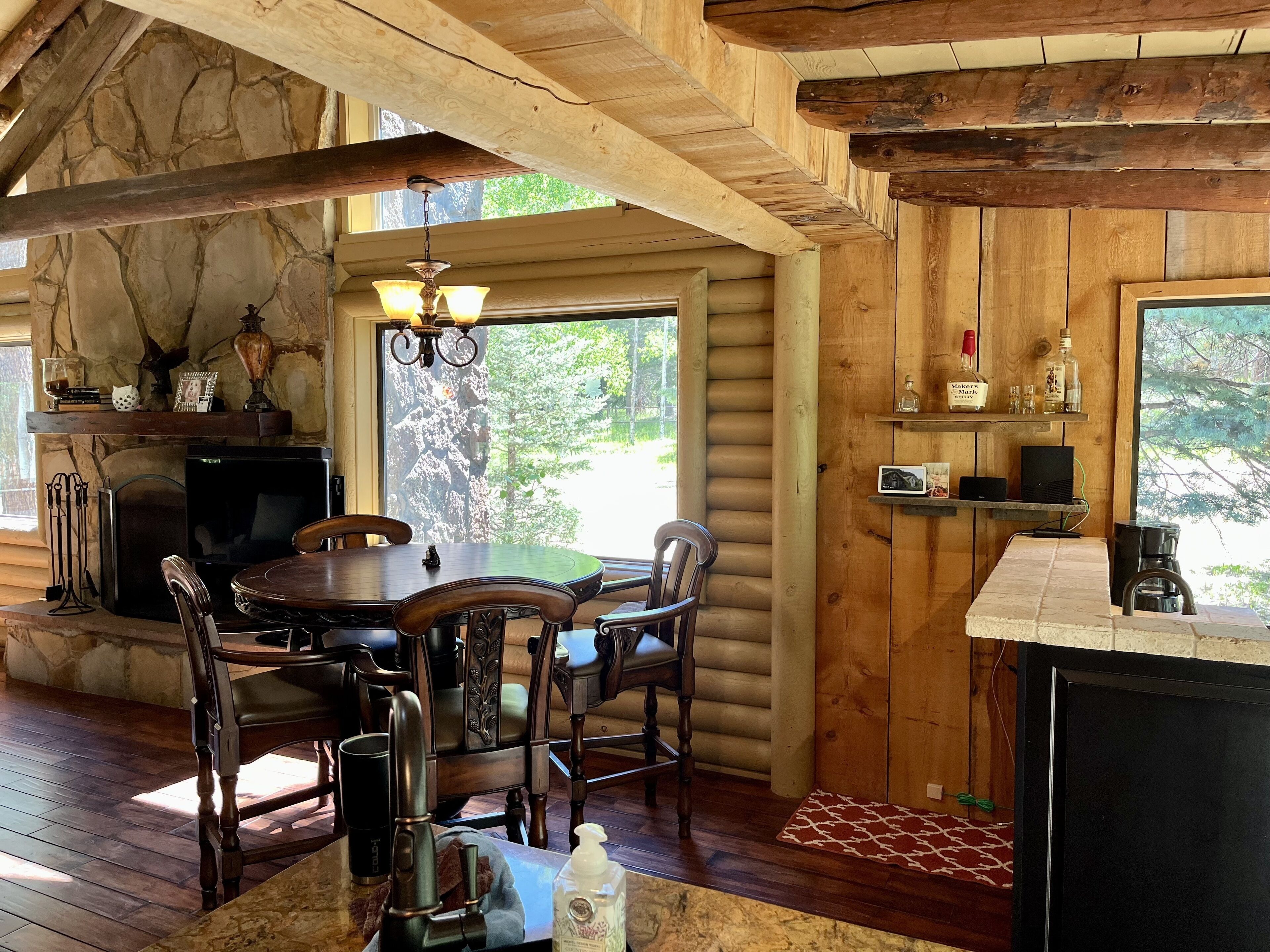 Ein rustikales Blockhaus-Interieur mit einem Holzespeisesaal, Stühlen, einem Kamin und einer Steinwand.
