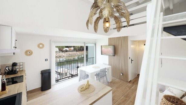 Uma sala de estar moderna com área de jantar, TV na parede e varanda com vista para o exterior.