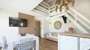 Uma sala de estar moderna com televisão de tela plana, uma mesa de jantar com cadeiras, um sofá e uma máquina de lavar.