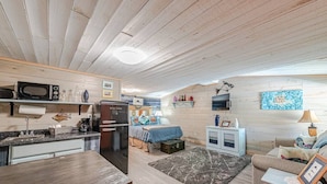 Um espaço de estar compacto com cozinha compacta, uma cama com roupa de cama colorida, um pequeno espaço de refeições e uma área de estar acolhedora.