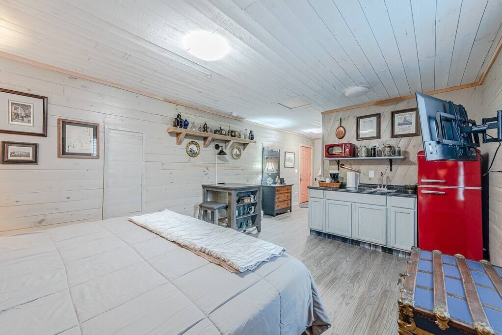 Quarto com cama, cozinha compacta e área de refei ções.