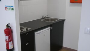 Eine kleine Küche mit Geschirrspüler, zwei Spülen und einem Feuerlöscher.