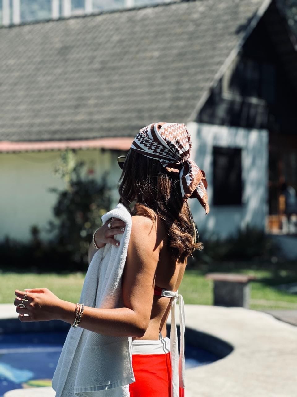 Una persona de pie junto a una piscina, con una casa al fondo.