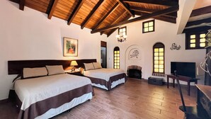 A hotel room with two beds, a fireplace, a television, and a staircase. - Hotel Rancho Grande (Panajachel)