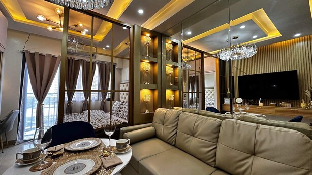 A modern living room with a sofa, a dining table set with plates and glasses, and a large flat-screen TV. - Deluxe Suit Room (Pasay)