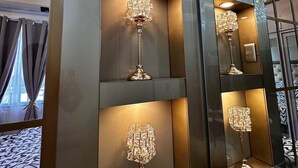 A modern hotel room with a large mirror reflecting a chandelier and a sofa. - Deluxe Suit Room (Pasay)