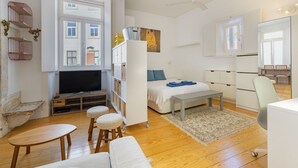 A modern living room with a sofa, a coffee table, a TV, and a bookshelf. - Fully new refurbished Alfama Central Cosy Home (Lisboa)