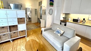 A compact living space with a kitchenette, a dining area, and a sofa with a decorative pillow. - Fully new refurbished Alfama Central Cosy Home (Lisboa)