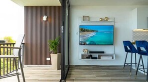 Relax in this stylish living room with a flat-screen TV, decorative shelf, and comfortable seating area.