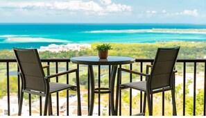 Enjoy the serene coastal view from this balcony with a table and two chairs.