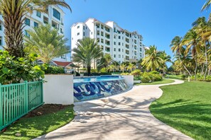 Un hôtel moderne doté d’une piscine, entouré de palmiers et d’une pelouse bien entretenue.