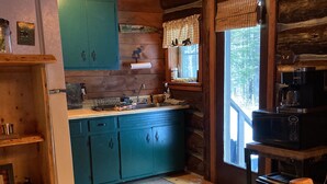Cocina rústica con armarios de madera, un refrigerador, una cafetera y un tostador.