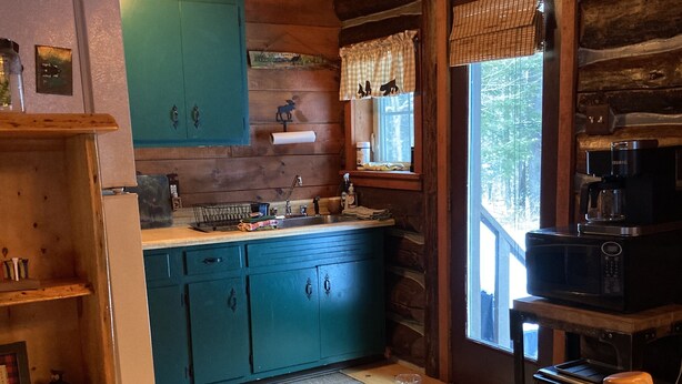 A rustic cabin kitchen with wooden cabinets, a refrigerator, a coffee maker, and a toaster. - PET FRIENDLY Adirondacks Log Cabin! Lake George, Saratoga, SPAC, Sacandaga (Stony Creek)