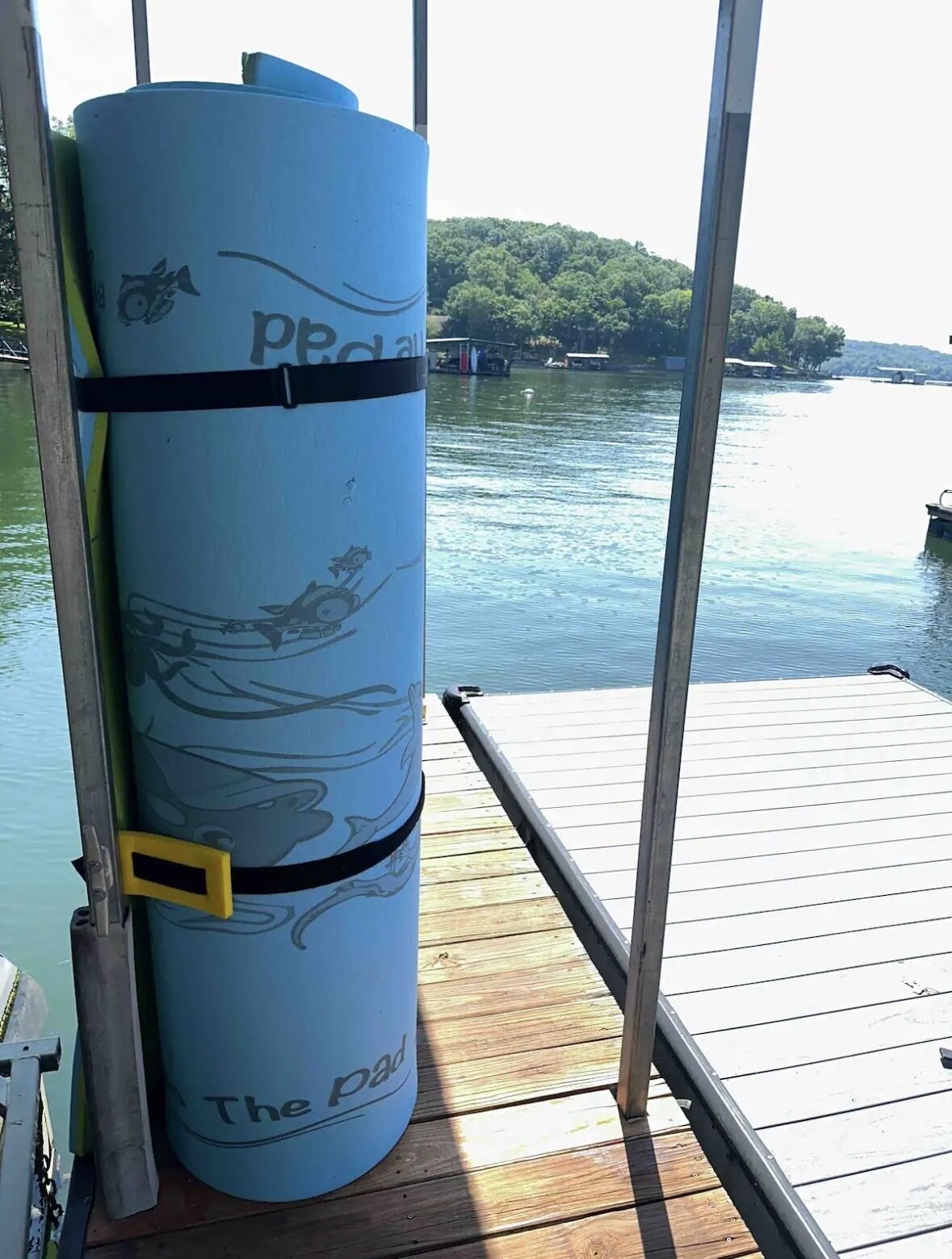 Un kayak bleu sur lequel on peut lire l’inscription « The pad », solidement attaché à un quai grâce à une rambarde métallique.