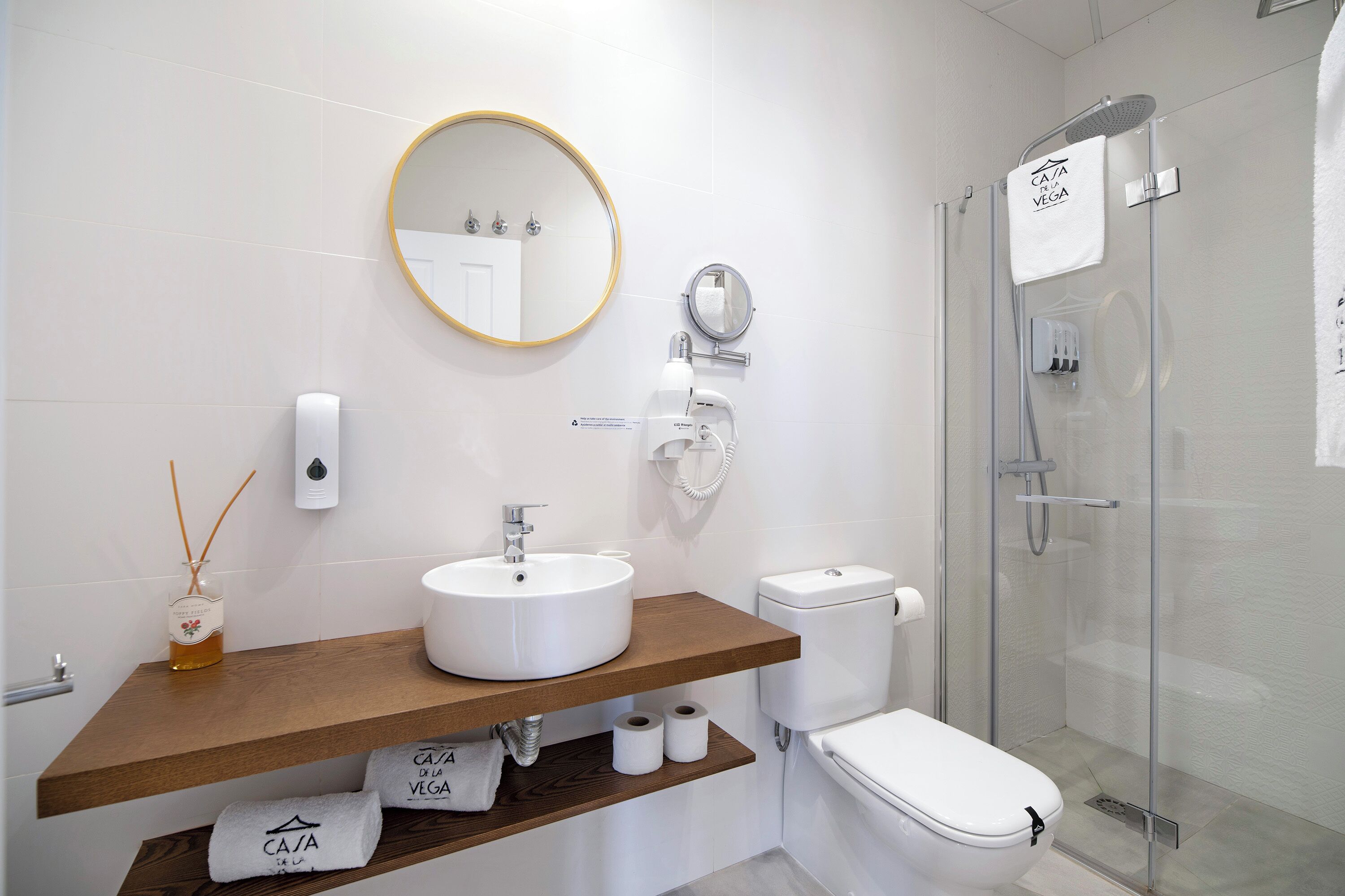 A modern bathroom with a round mirror, white sink, and glass shower enclosure.