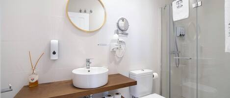 A modern bathroom with a round mirror, white sink, and glass shower enclosure.
