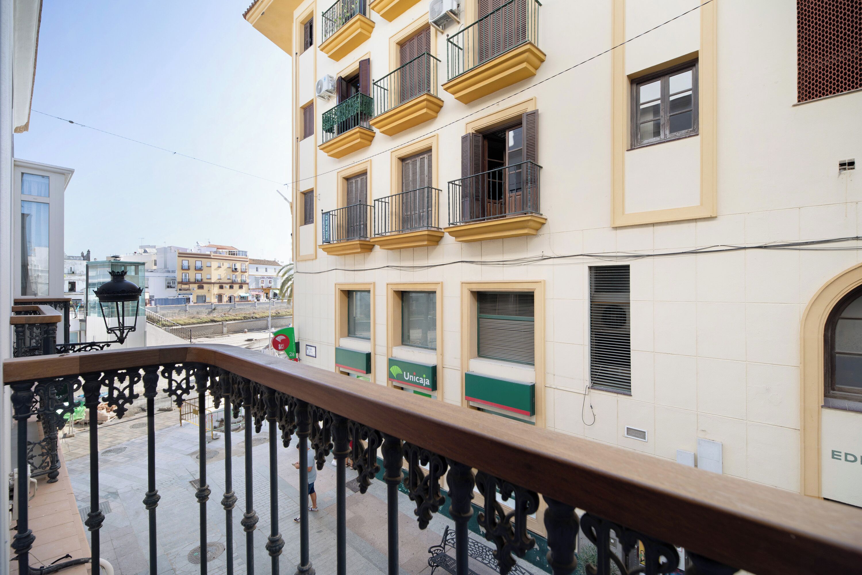 A balcony with a wrought iron railing overlooking a street with buildings.