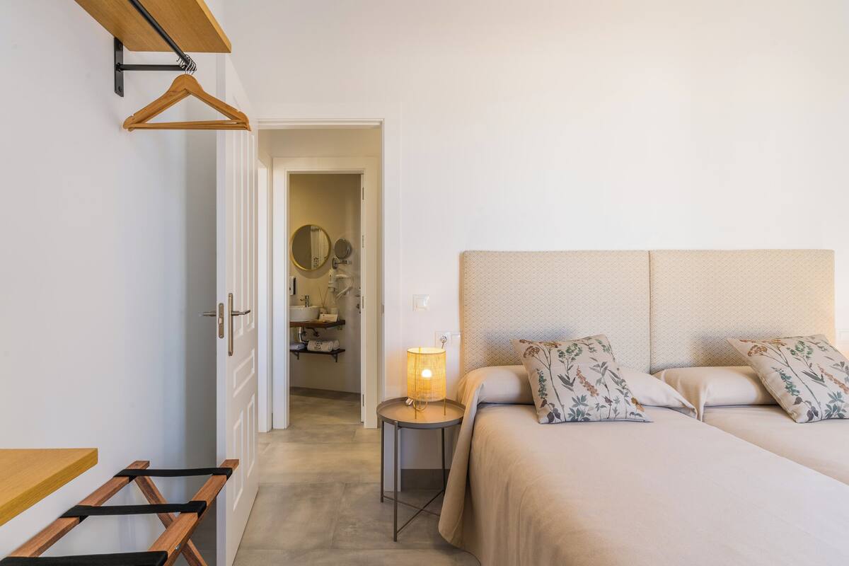 A bedroom with a bed, bedside table, and a hanging rack.
