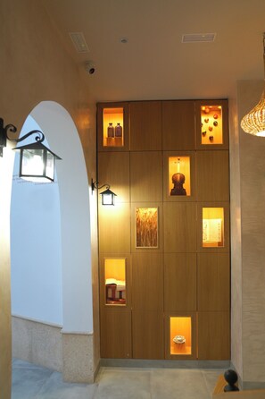 A hallway with a wooden panel wall, recessed lighting, and a decorative lamp.