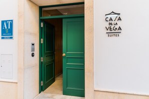 A hotel entrance with a green door, a keypad, and a sign for 'Casa de la Vega Suites'.