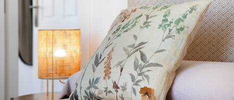Een bed met een bloemenkussen, een lamp en een behang met patroon.