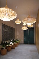 A hallway with multiple potted plants, a patterned wall, and a green door.
