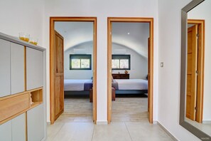 Une chambre à coucher avec un lit, une table de chevet et une fenêtre. On y trouve une armoire avec un miroir et une étagère avec deux verres.
