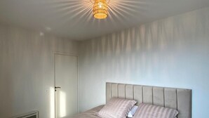 A bedroom with a bed, a radiator, and a ceiling light fixture. - Appartement + Parking Privé Gratuit (Marseille)