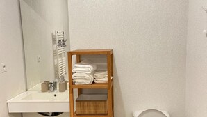 A bathroom with a sink, mirror, towel rack, and toilet. - Appartement + Parking Privé Gratuit (Marseille)