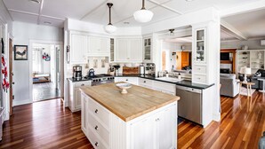 A spacious kitchen with white cabinetry, a wooden island, and a central island with a sink. - 2024 Updates Riverfront Home w/ Private Dock Close To Dock Square! Dogs Allowed! (Kennebunk)