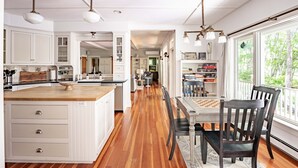 A spacious kitchen with wooden flooring, white cabinetry, and pendant lighting. - 2024 Updates Riverfront Home w/ Private Dock Close To Dock Square! Dogs Allowed! (Kennebunk)
