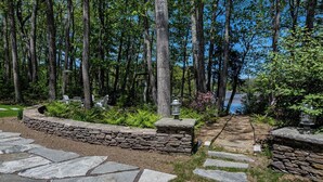 A stone pathway leading through a forested area with a stone wall and benches. - 2024 Updates Riverfront Home w/ Private Dock Close To Dock Square! Dogs Allowed! (Kennebunk)