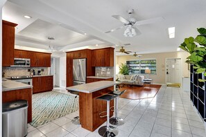 Une cuisine moderne avec des meubles en bois, des appareils électroménagers en acier inoxydable et un coin bar.