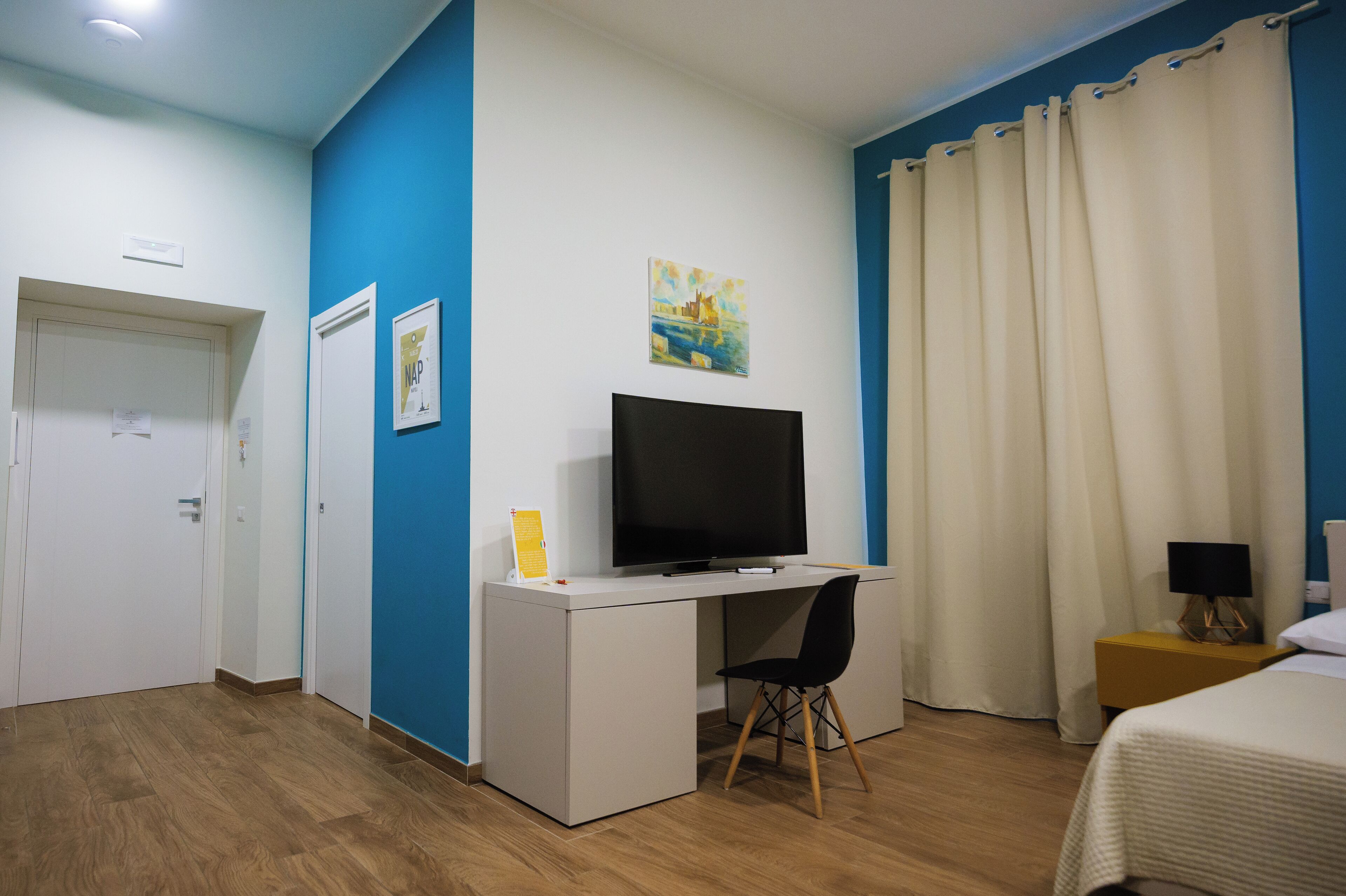 Ein Hotelzimmer mit Schreibtisch, Fernseher, Bett und Nachttisch.