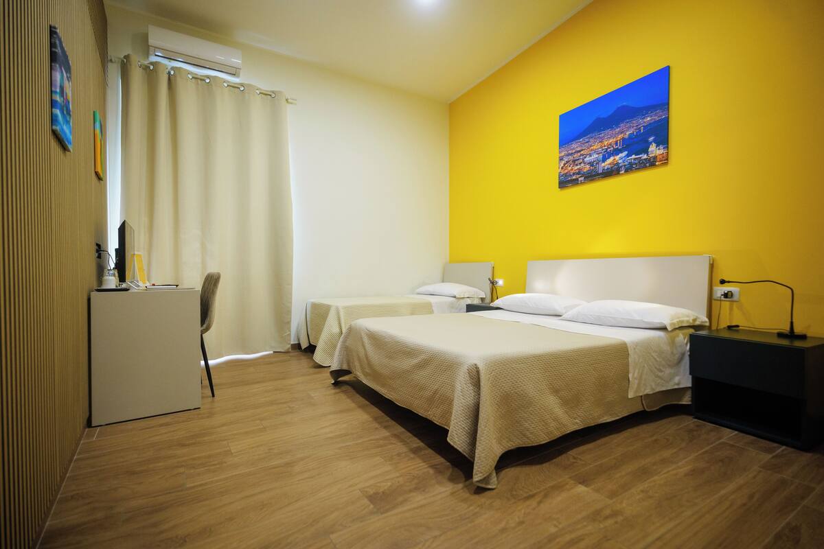 Une chambre d’hôtel avec deux lits, un bureau et une chaise.