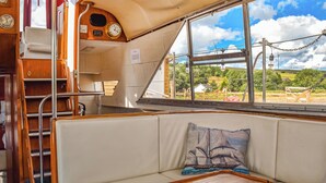 Ein gemütliches Blockhaus mit gepolsterten Sitzgelegenheiten, einem Holztisch, einer Uhr und einem Fenster mit schöner Aussicht.