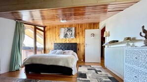 Et soveværelse med træloft, en seng med sengegavl, et ulvemaleri, en dør og en radiator.