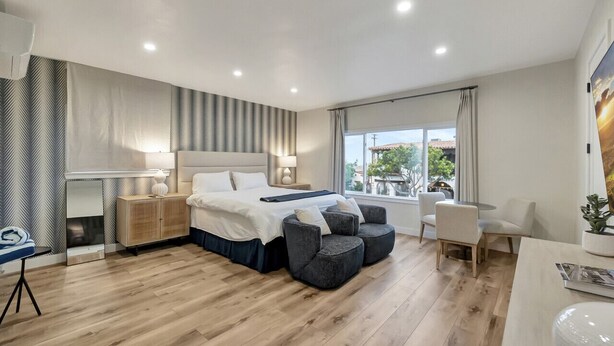 A modern hotel room with a large bed, a desk, and a seating area. - Coastal studio w/ beach access & free parking (San Clemente)