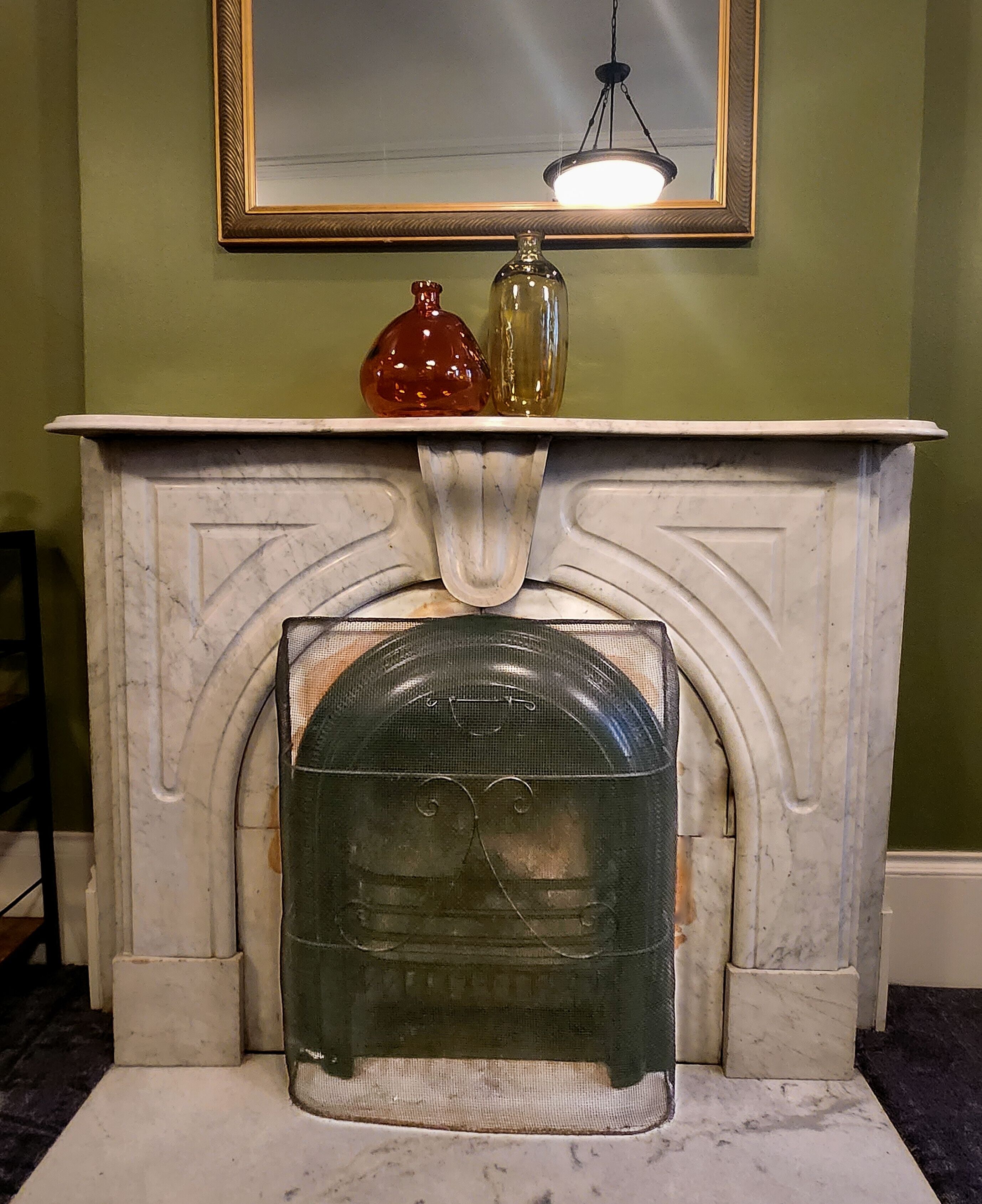 A fireplace with a white mantel, a mirror above it, and two decorative vases.