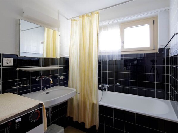 A bathroom with a white sink, a bathtub, and a mirror.