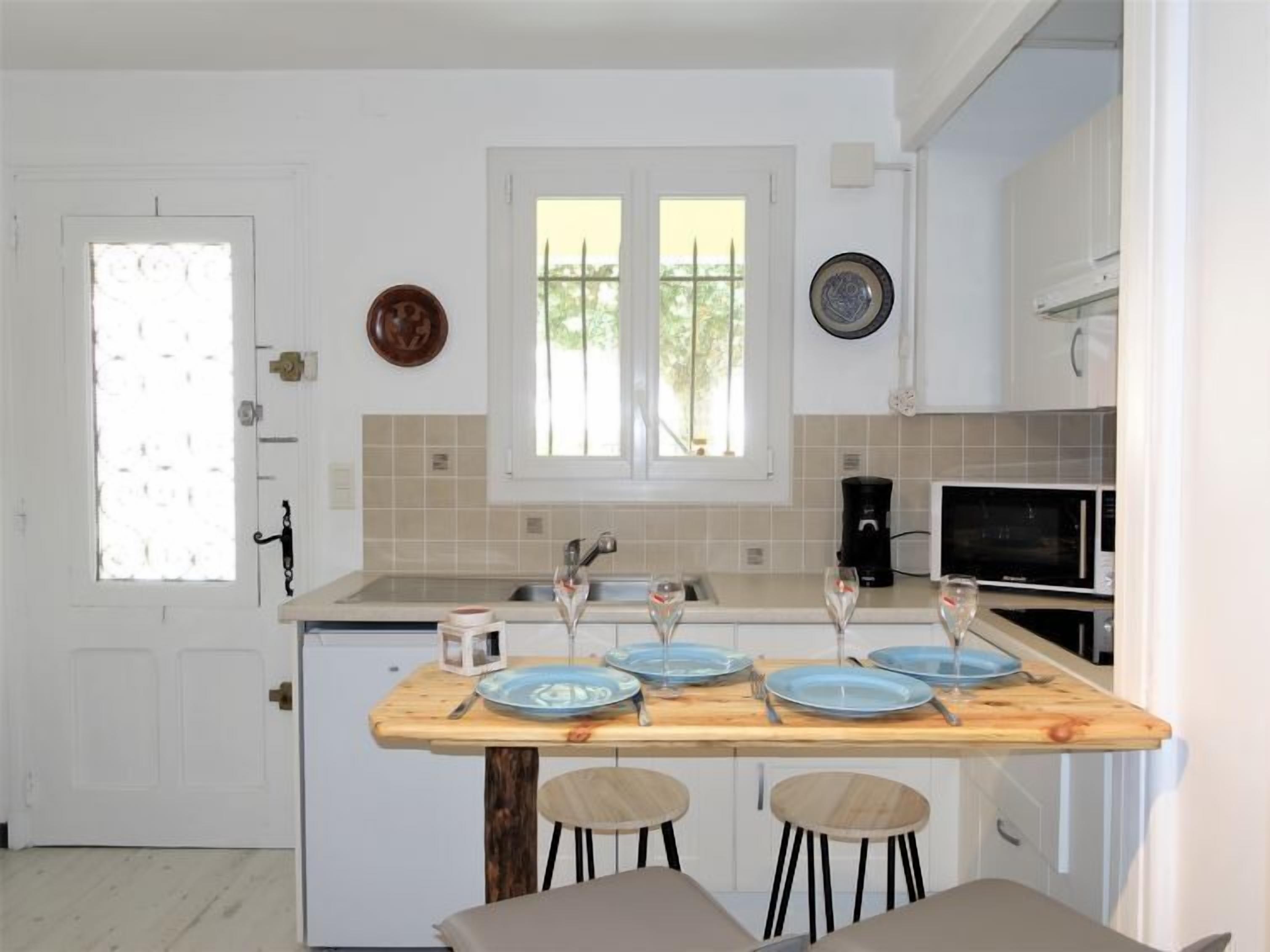 Een kleine keuken met een houten bar, witte kasten, een magnetron en een koffiezetapparaat.